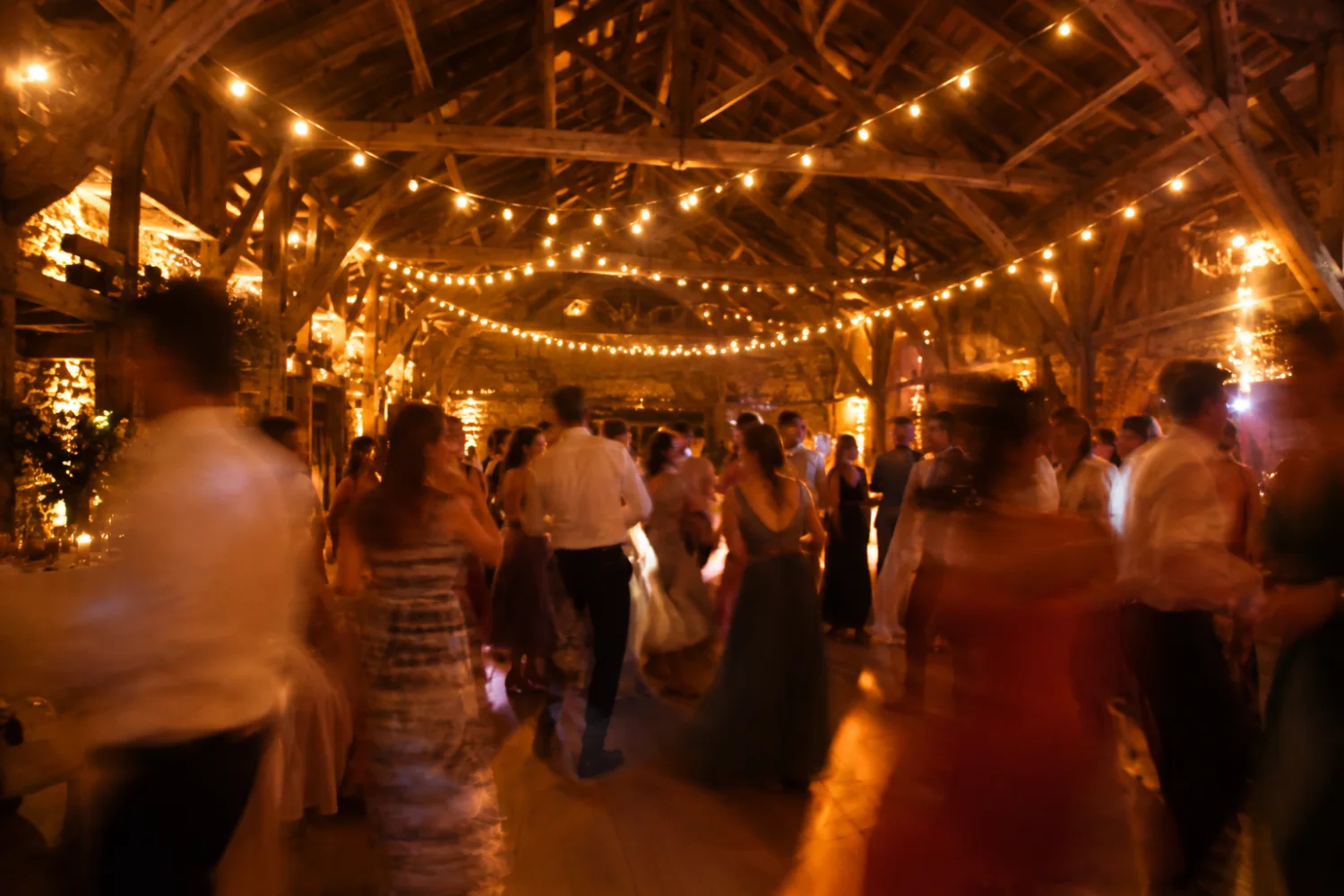 Une piste de danse sous une charpente ancienne et des guirlandes lumineuses
